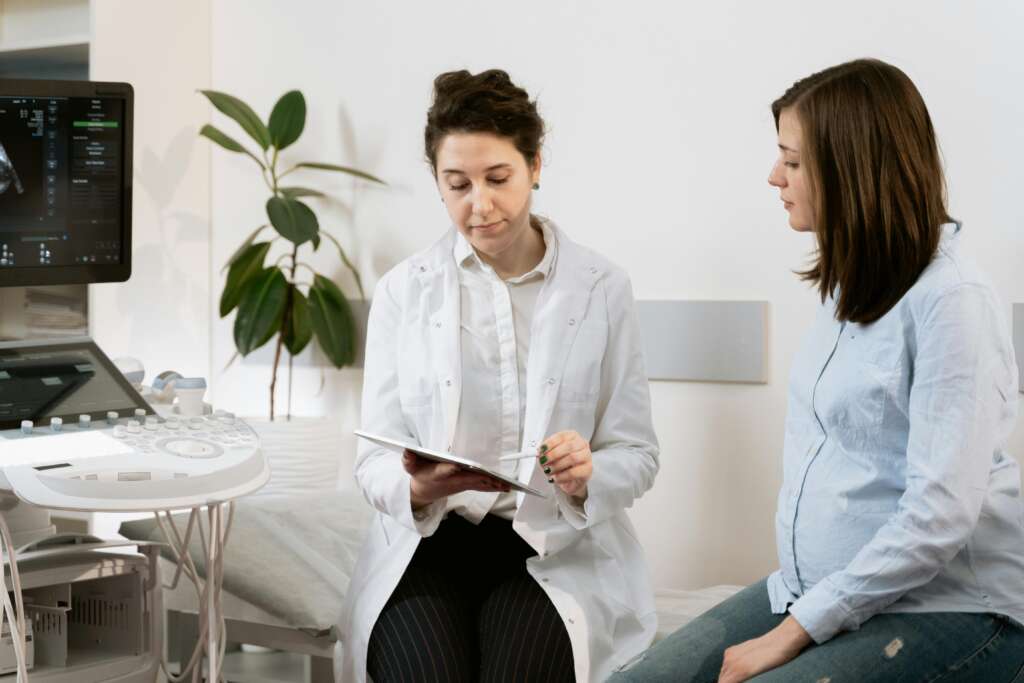 Doctor consulting pregnant woman with ultrasound machine in a medical clinic.